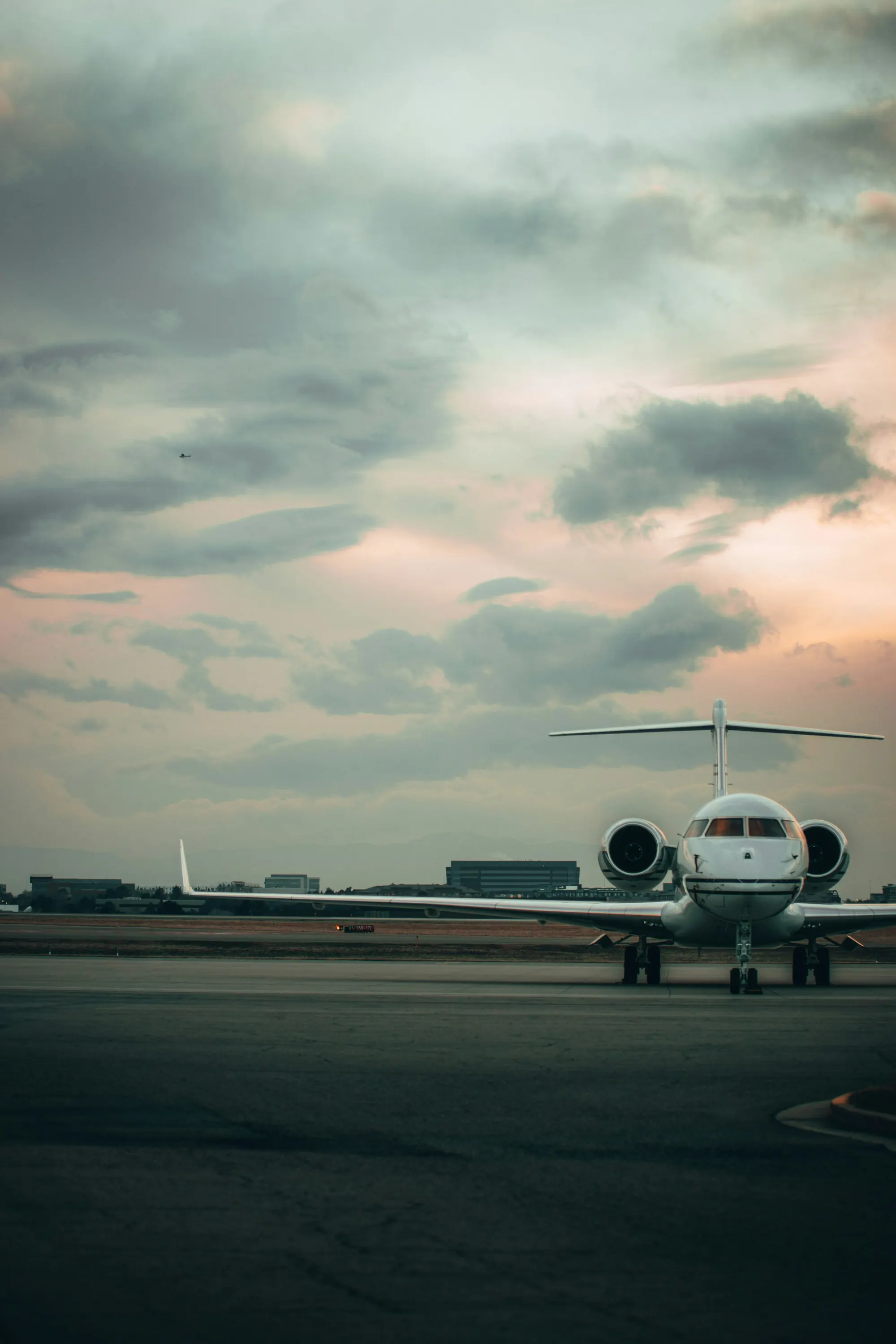 Business jet waiting on an airport ramp at dusk under a wide evening sky